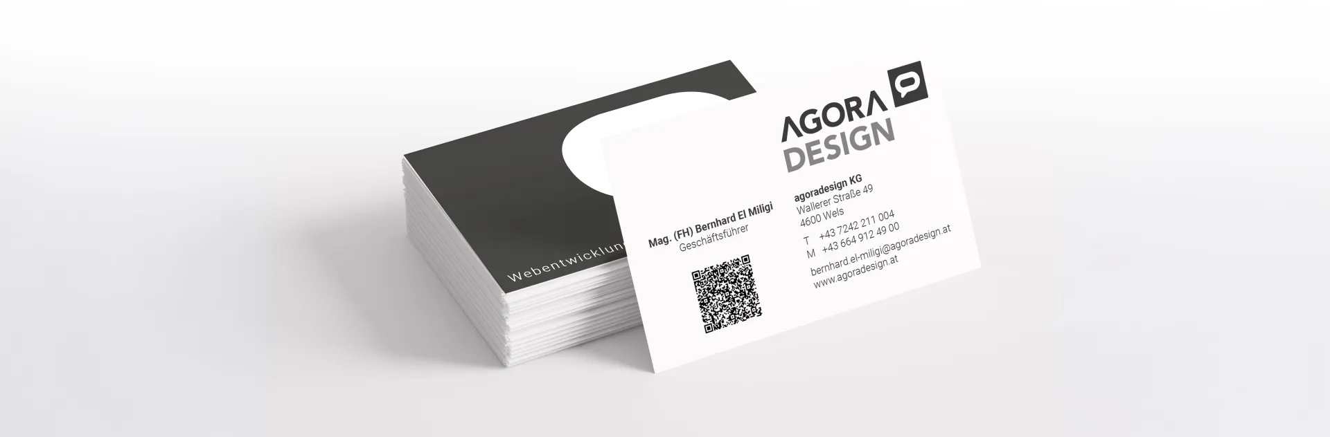 Visitenkarte mit Logo und QR-Code auf schwarzem Kartenhalter.