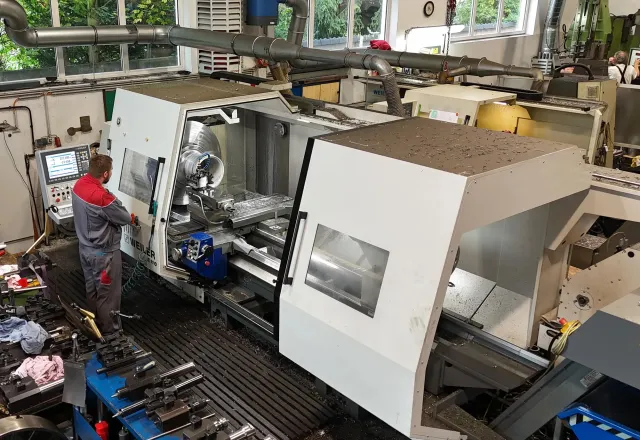 Industrielle Fertigungsanlage mit Arbeiter in einer Werkhalle.