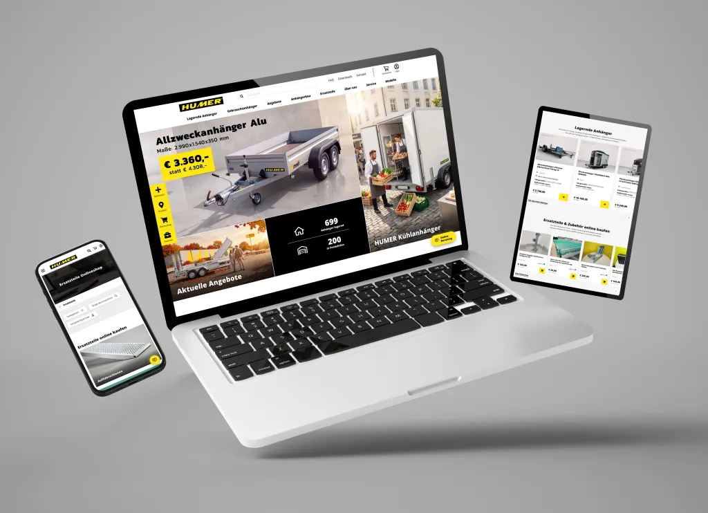 Schwebender Laptop mit geöffnetem Onlineshop, Smartphone und Tablet vor grauem Hintergrund.